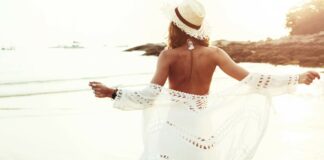 7 essentiels pour un week-end à la mer femme de dos sur la plage face à la mer