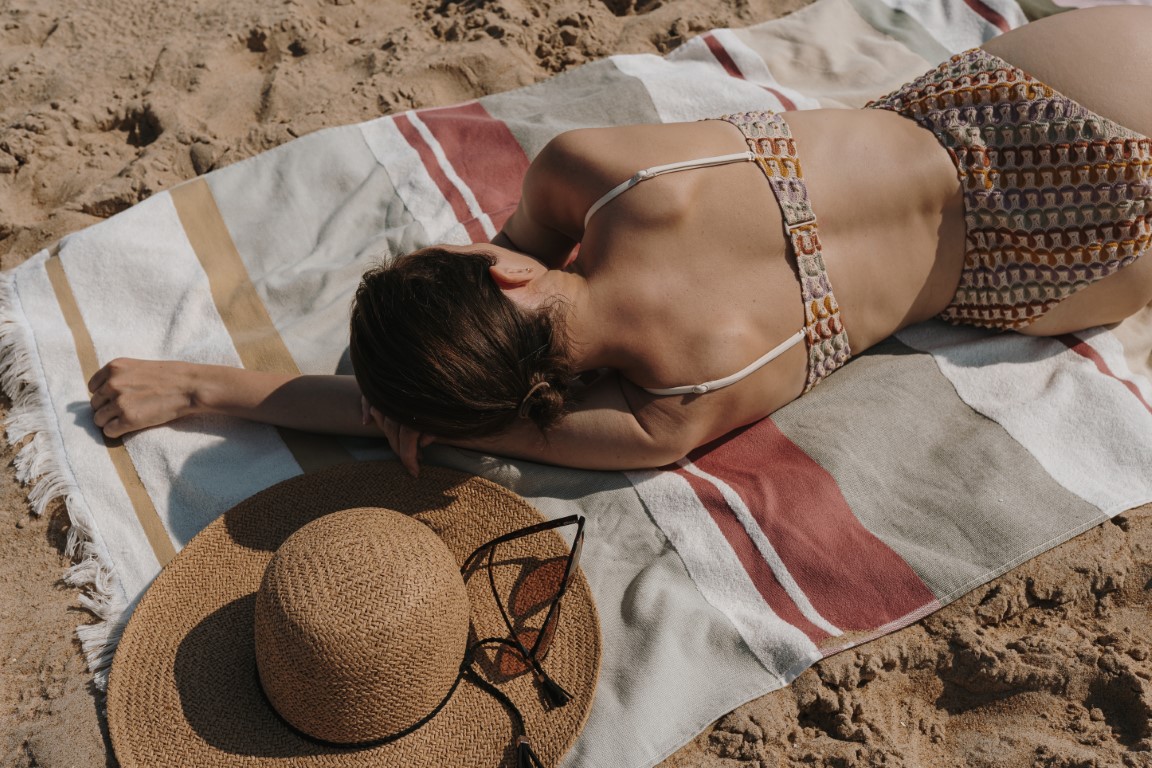 femme qui dort sur la plage avec un chapeau